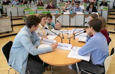 6 junge Redner diskutieren im Zentrum des Plenarsaals und werden dabei streng von der Jury bewertet 