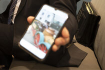 Eine Hand hält ein Smartphone, auf dem das Bild eines Nachbaus der Lok Saxonia zu sehen ist.